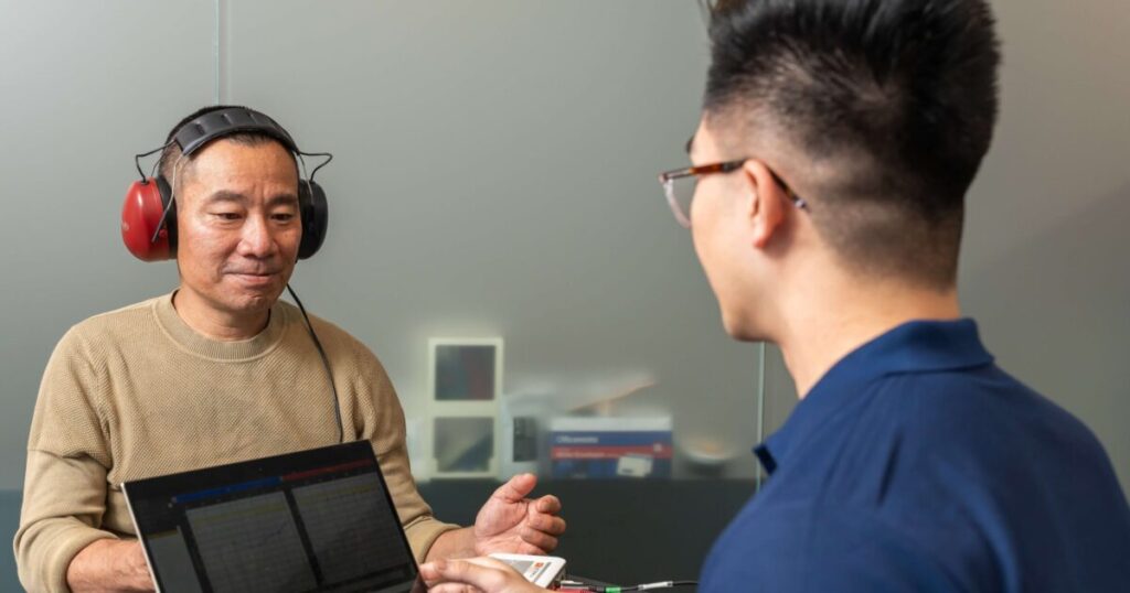 A health professional is performing workplace hearing test on a worker.